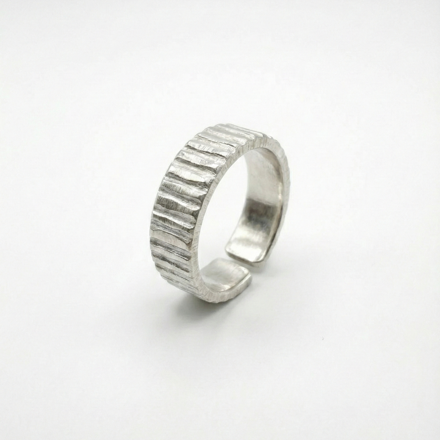 Silver ring with textured design on a white background