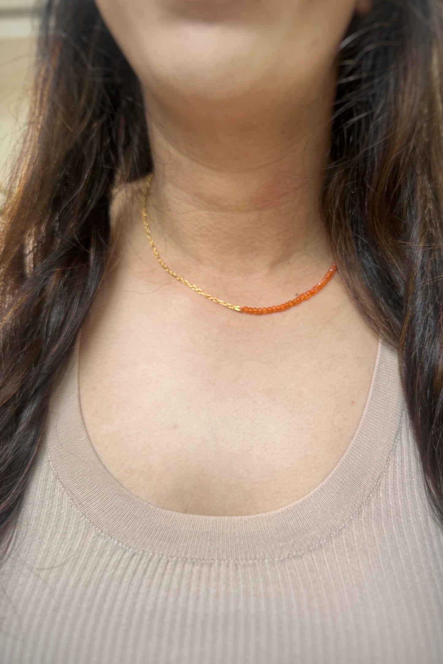Person wearing a gold necklace with a neutral background
