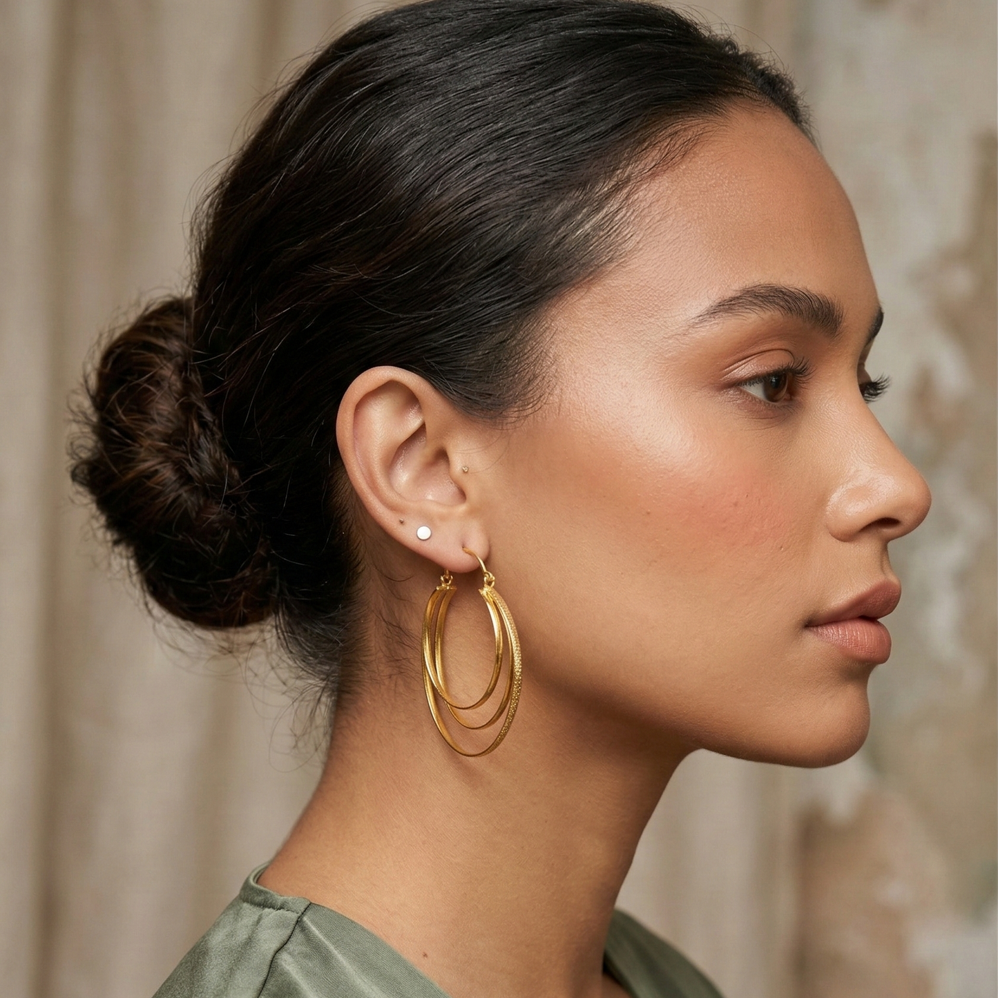 Woman wearing gold hoop earrings with a neutral background