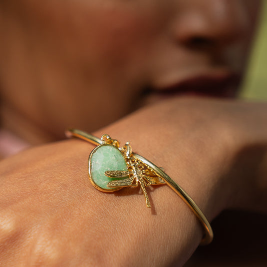 Gold bracelet with a green gemstone on a person's wrist