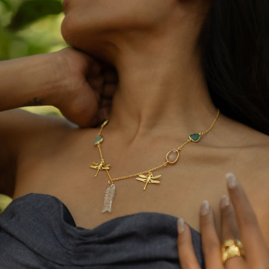 Gold necklace with charms worn by a person, with a blurred background