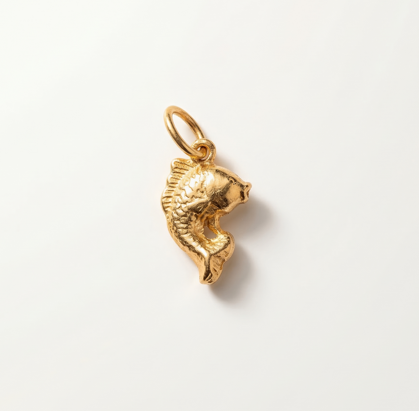 Gold fish-shaped pendant on a light gray background