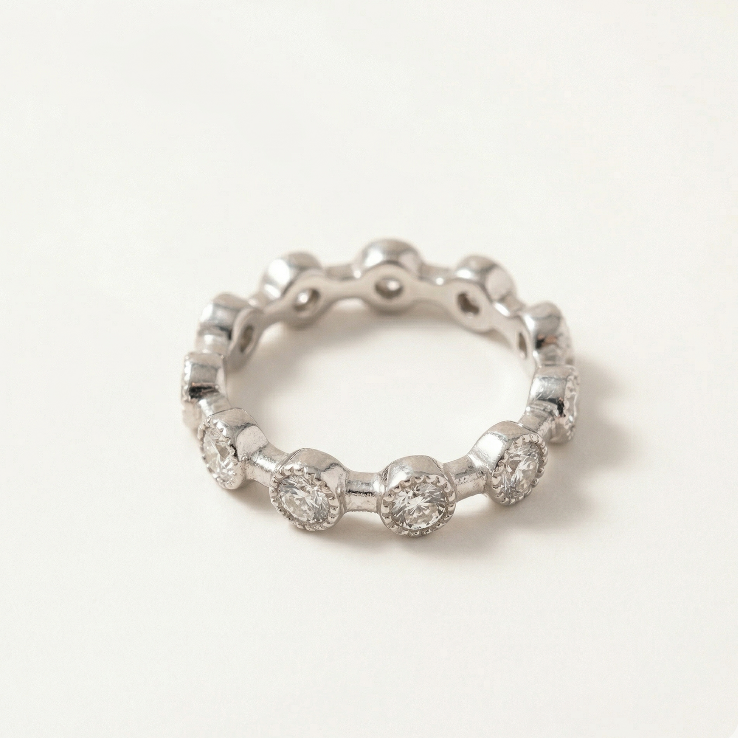 Silver ring with embedded zircon stones on a light gray background