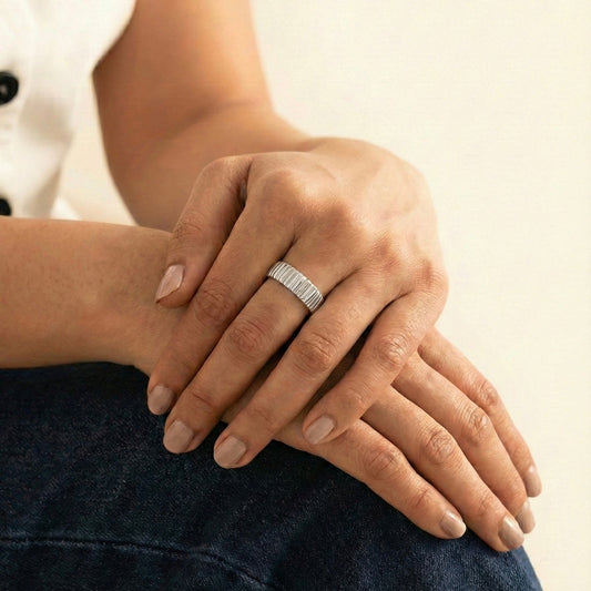 Close-up of a hand wearing a silver ring on a neutral background
