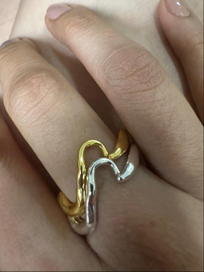 Gold and silver ring on a finger with a blurred background