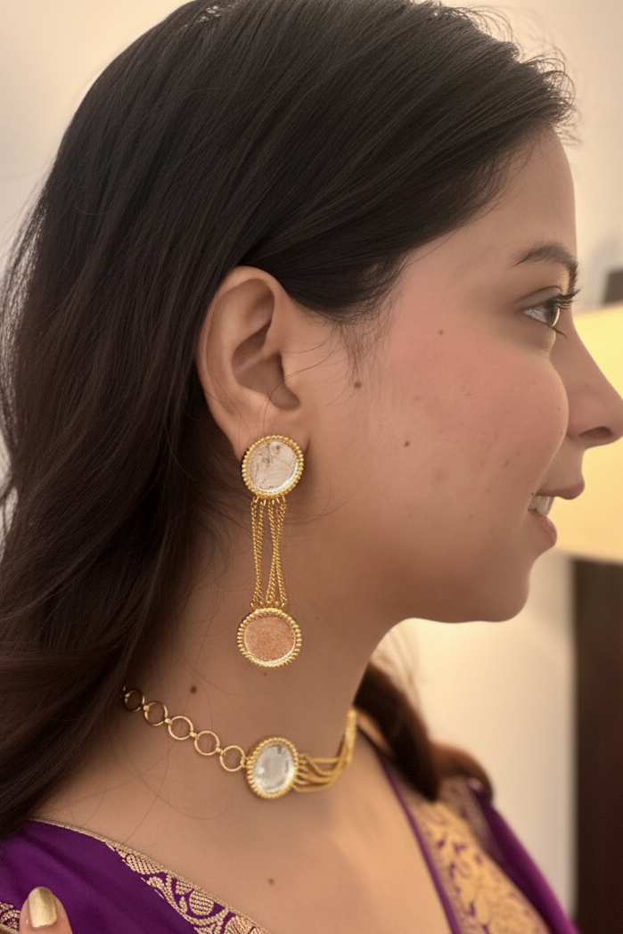 Woman wearing gold earrings and a necklace with a blurred background