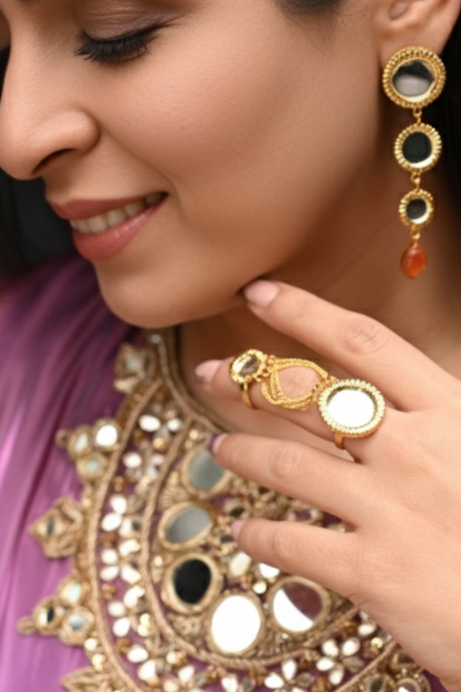 Woman wearing traditional jewelry including earrings, necklace, and ring, with a blurred background.