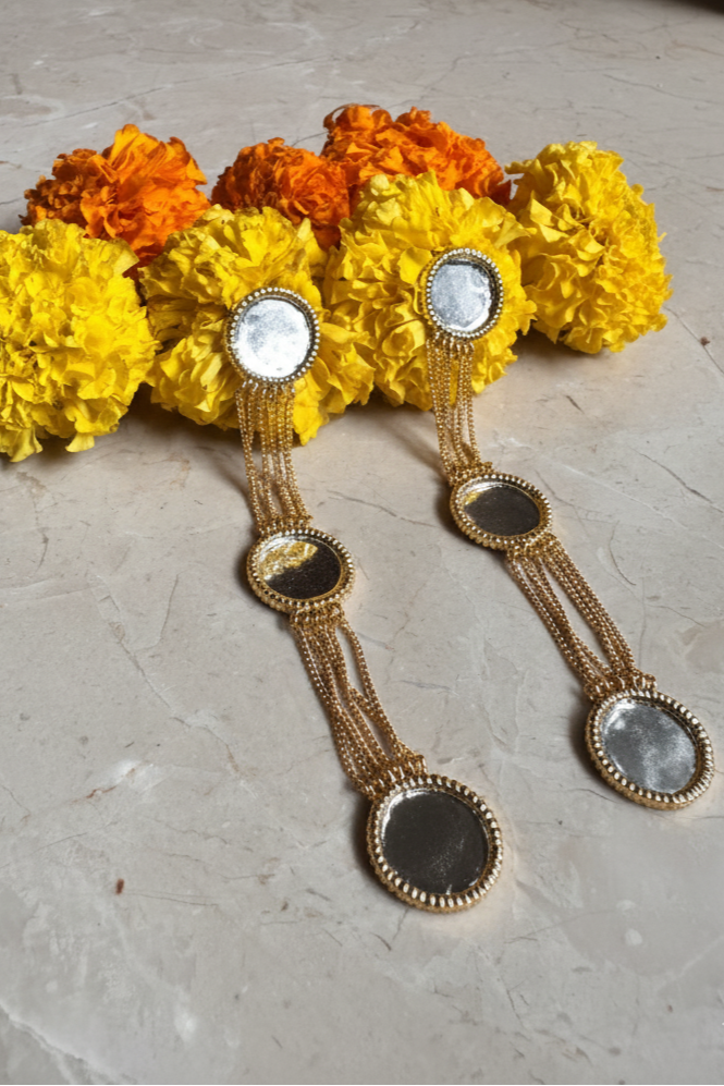 Decorative earrings with marigold flowers on a light surface
