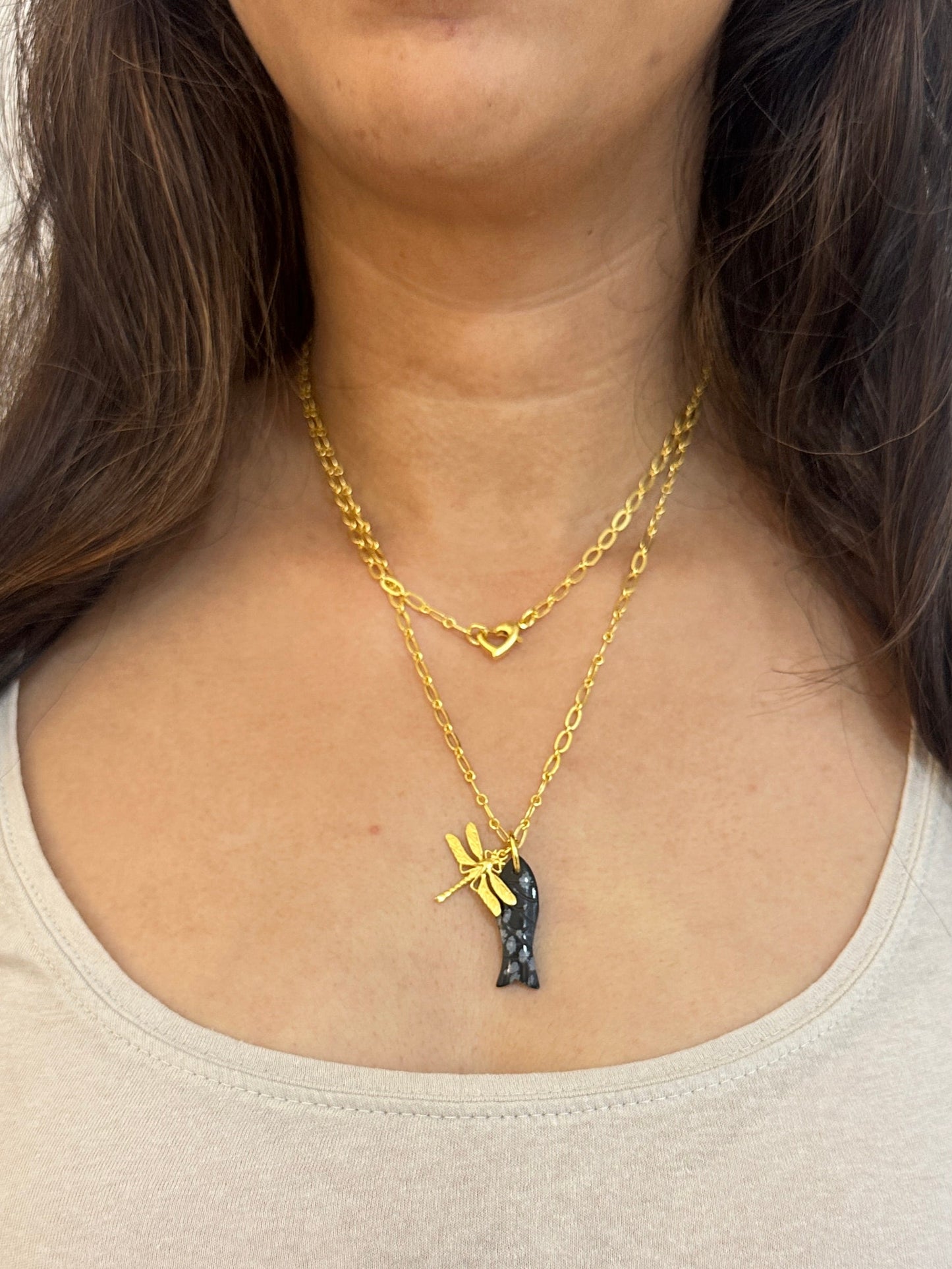 Woman wearing a gold necklace with a small pendant on a white background