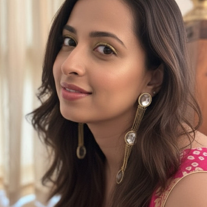 Woman with long brown hair wearing earrings indoors