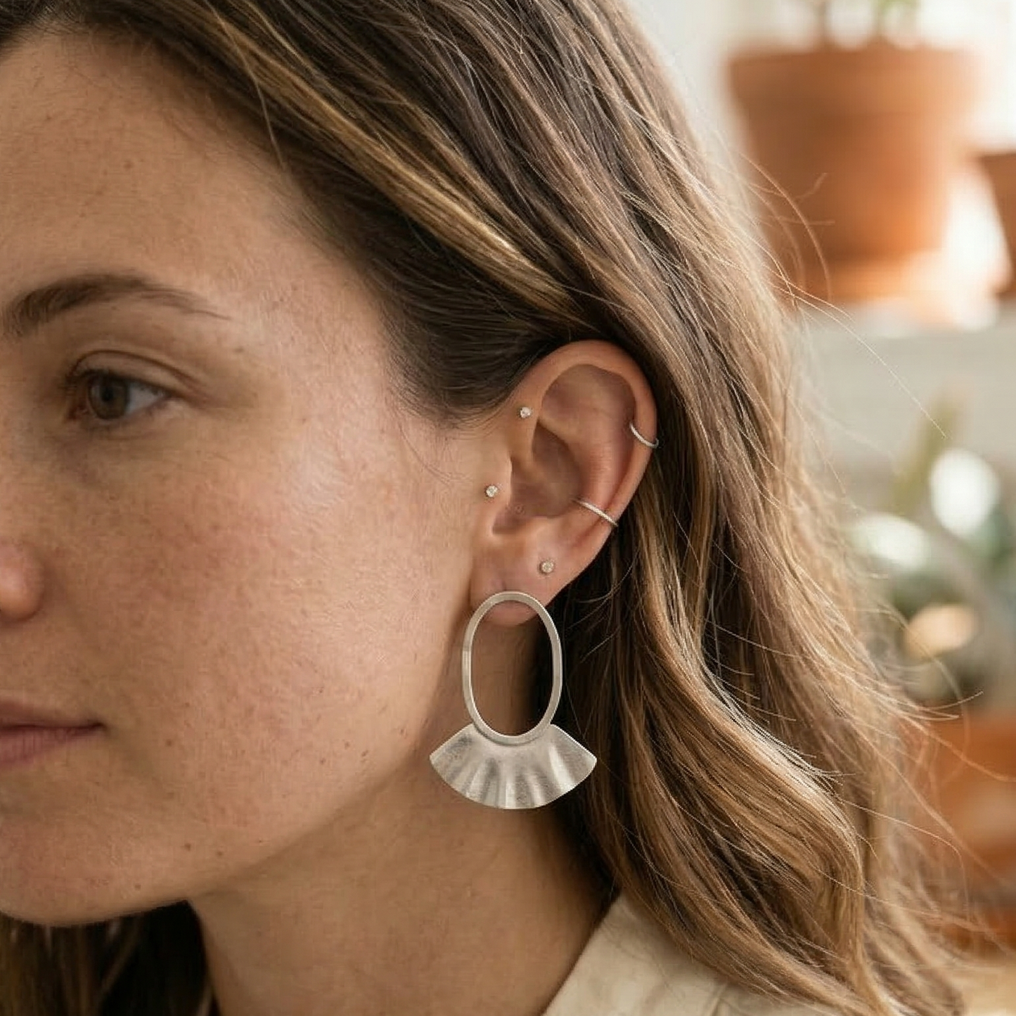 Woman wearing silver hoop earrings with a blurred indoor background