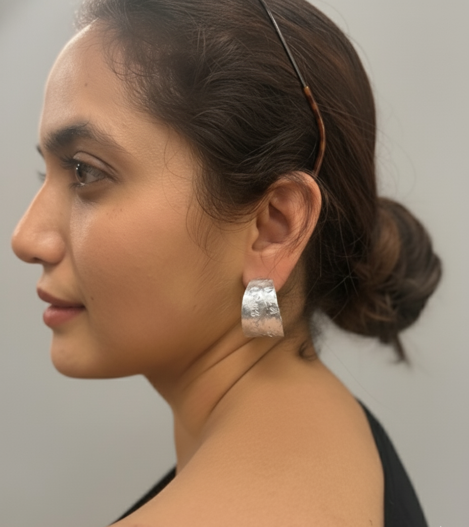 Woman wearing a silver earring with a plain background