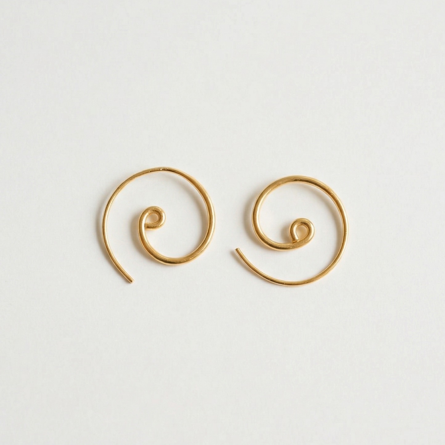Pair of gold spiral earrings on a light gray background