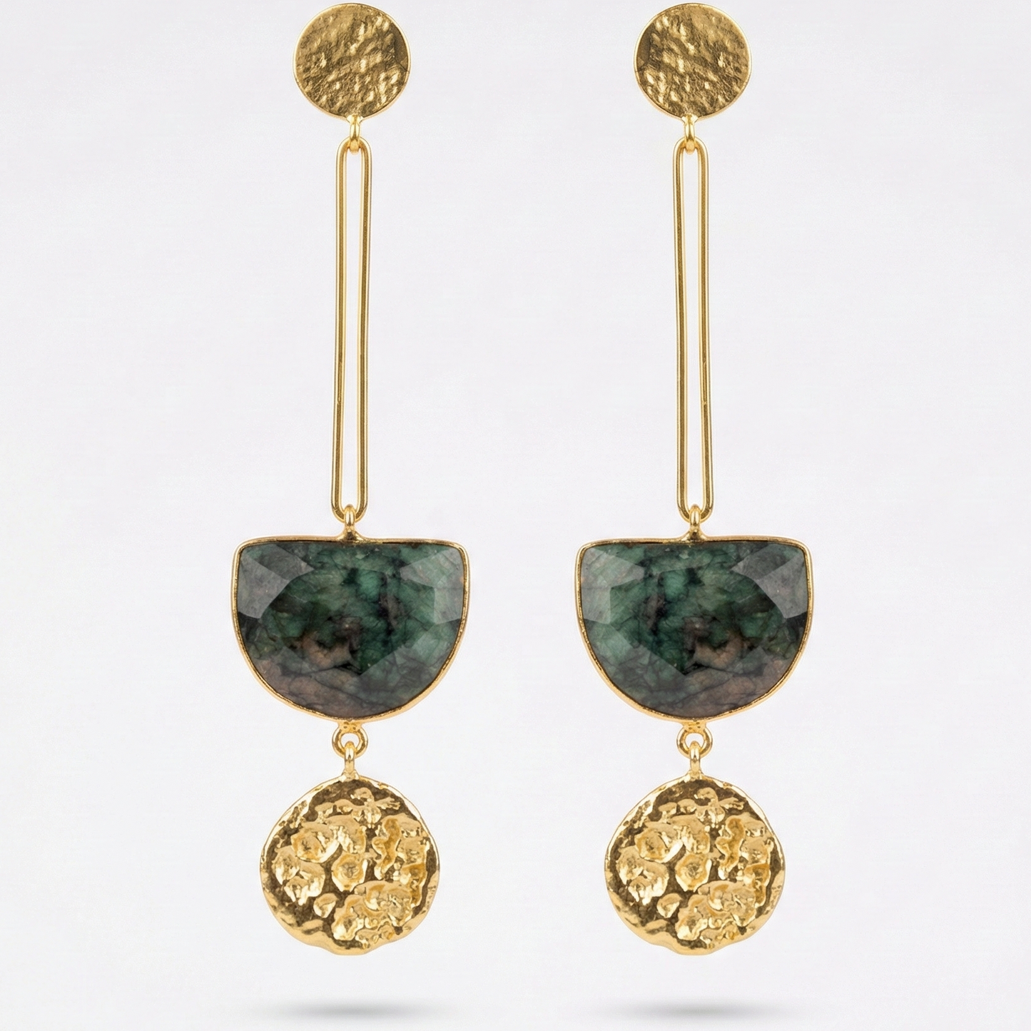 Gold and green earrings on a light gray background