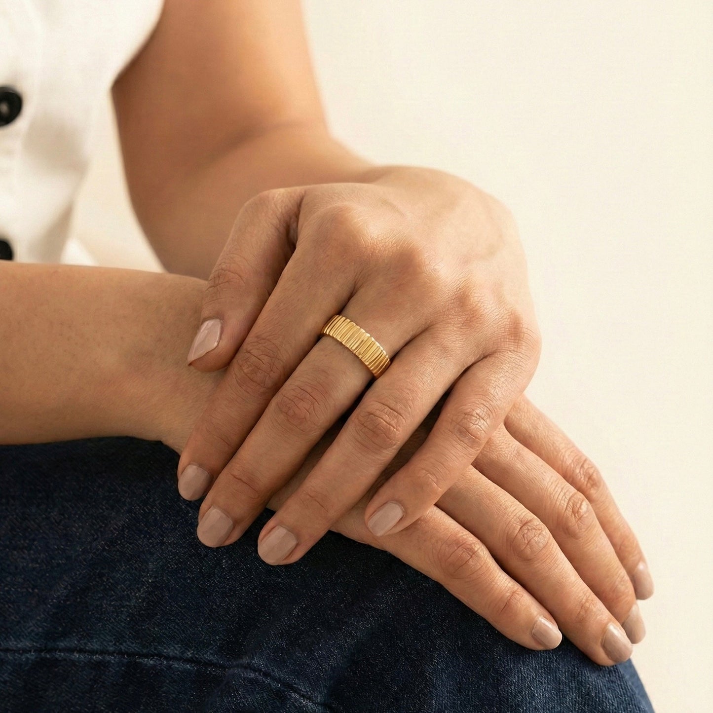 Close-up of a hand wearing a gold ring with a blurred background