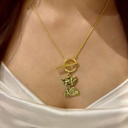 Gold necklace with a pendant on a person wearing a white top
