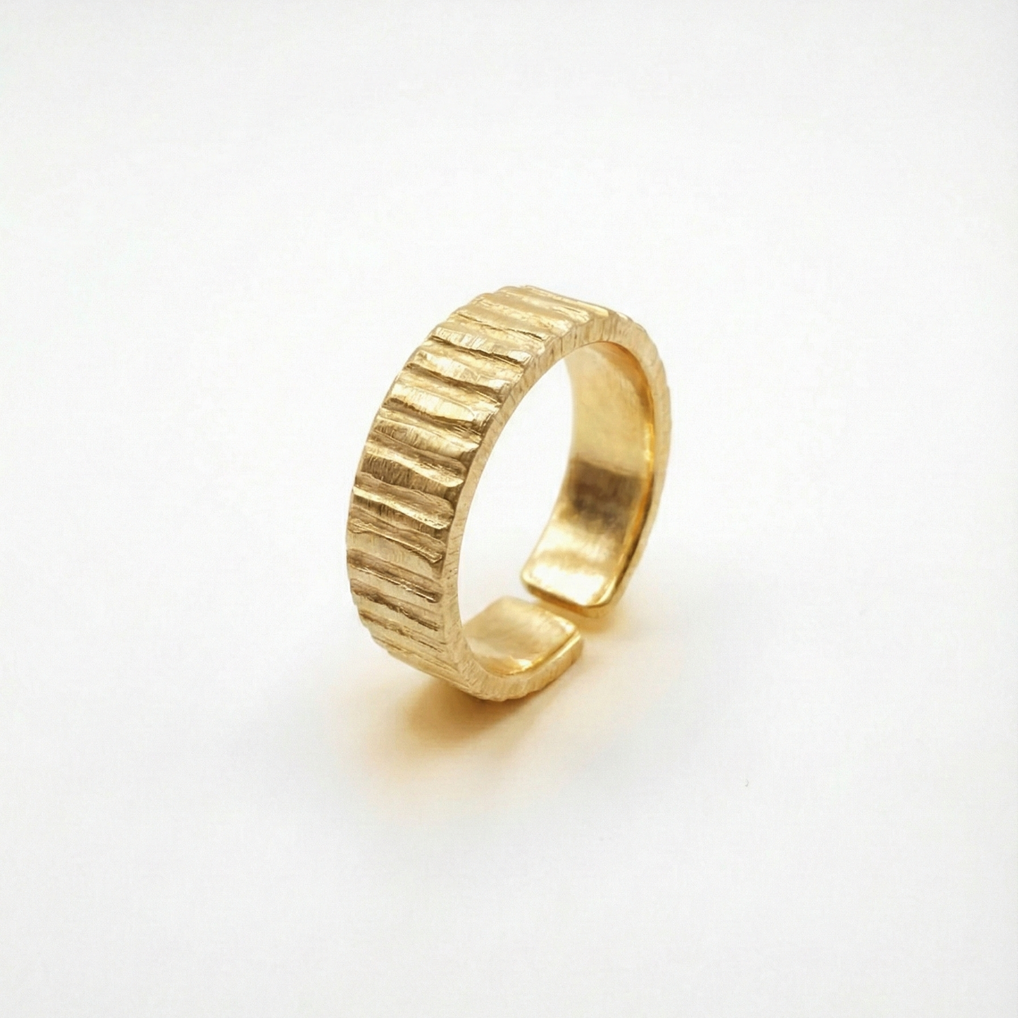 Gold ring with textured design on a white background