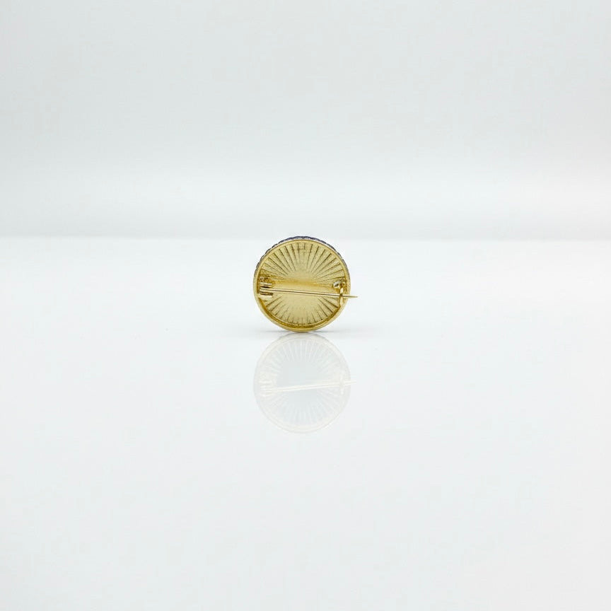 Gold circular brooch on a white background