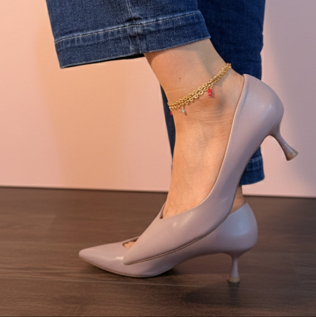 Light gray high-heeled shoes worn with blue jeans on a neutral background