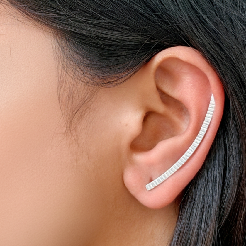 Close-up of an ear wearing a silver earring with a blurred background