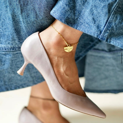 Close-up of beige high-heeled shoes with a person wearing blue dress.