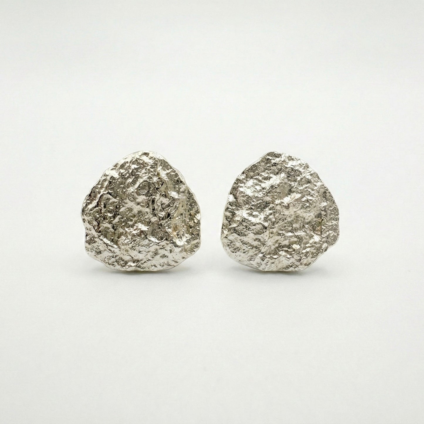 Pair of silver textured round earrings on a white background