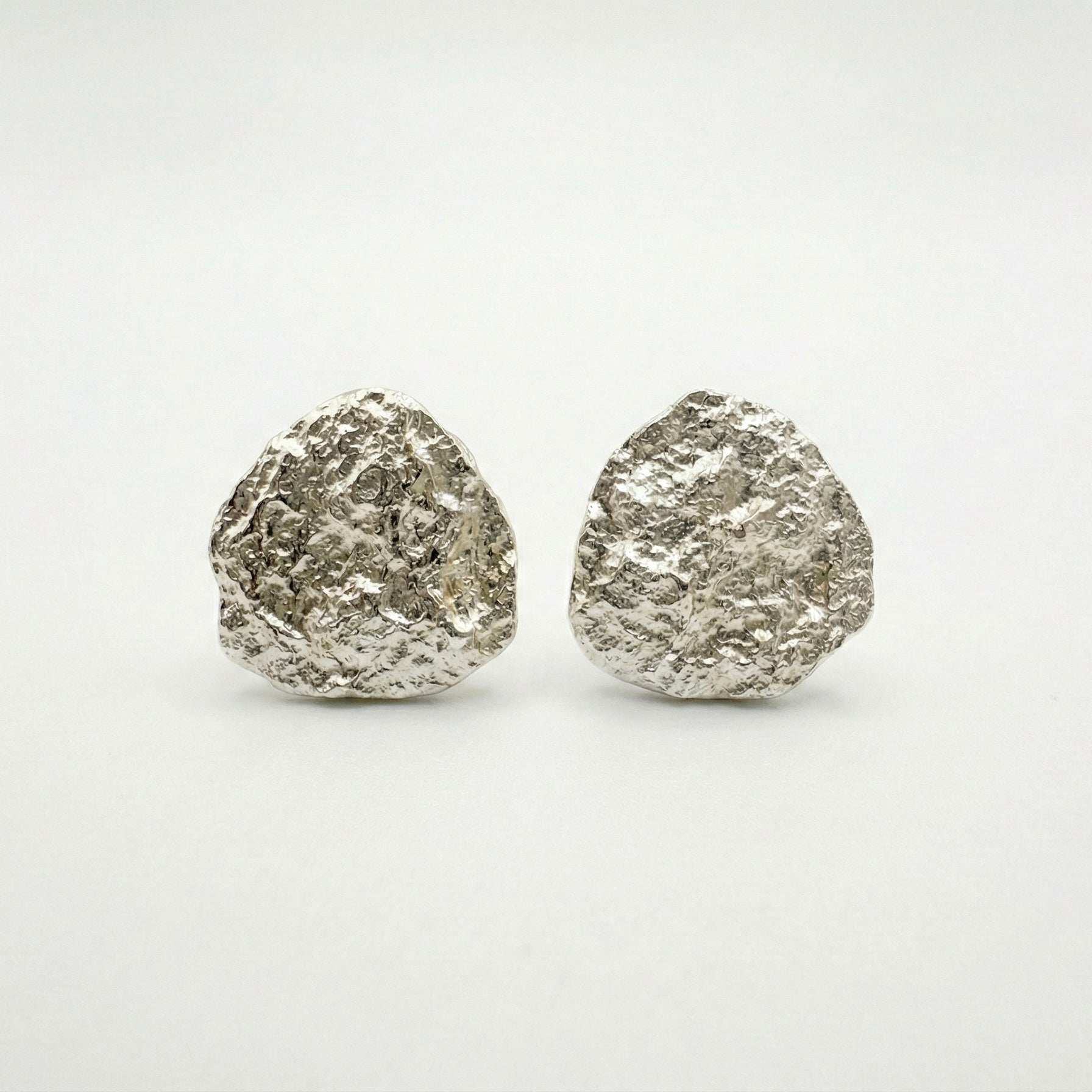 Pair of silver textured round earrings on a white background