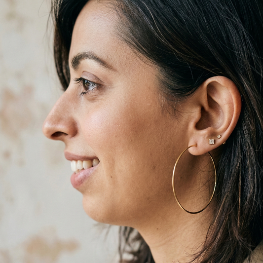 Woman wearing gold hoop earrings with a neutral background
