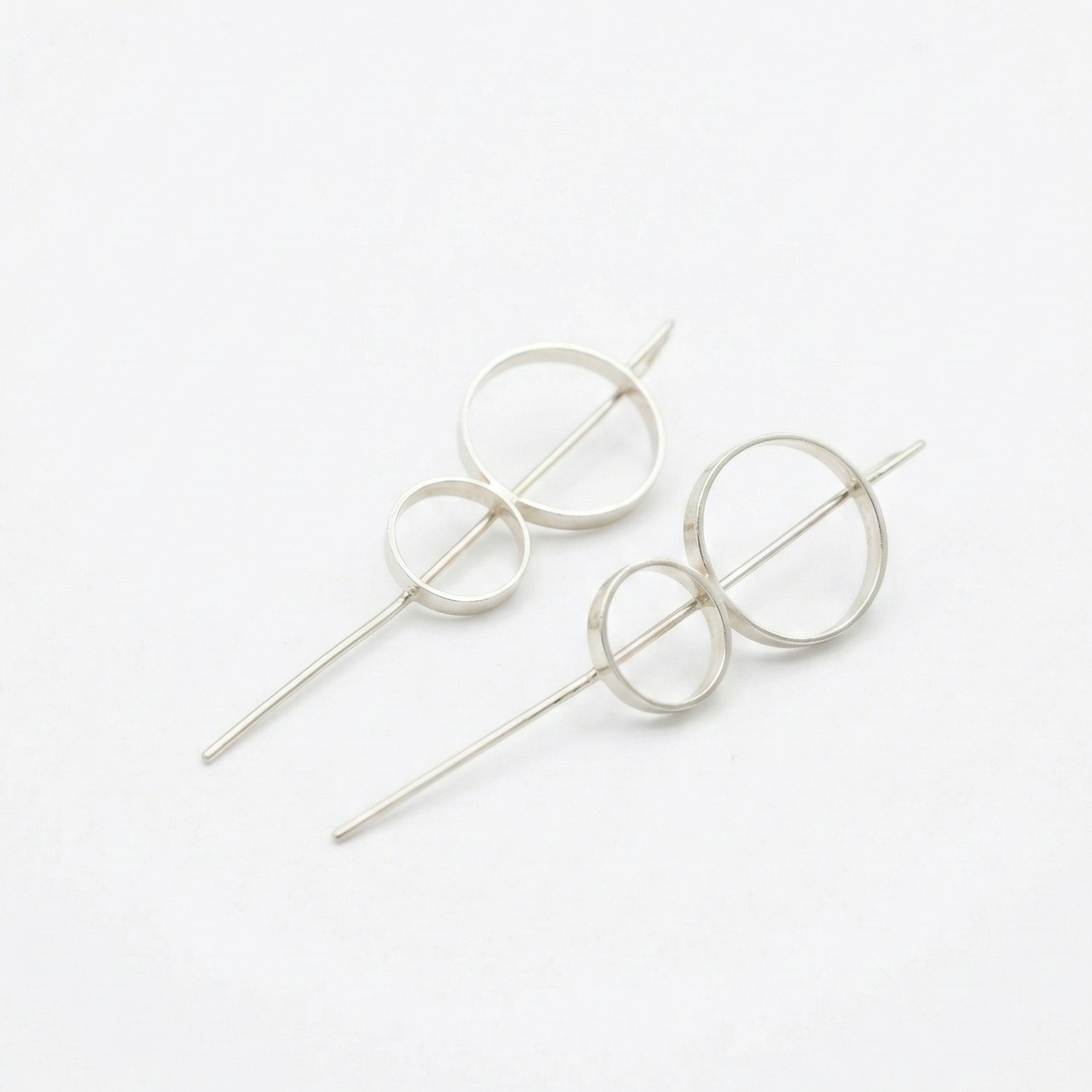 8 stick hoop earrings circular designs on a white background