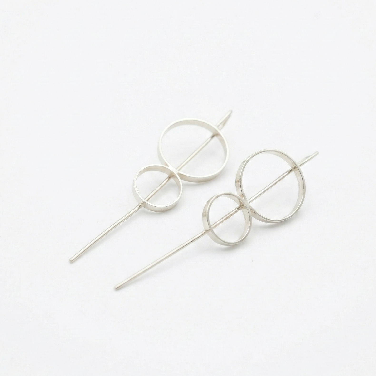 8 stick hoop earrings circular designs on a white background