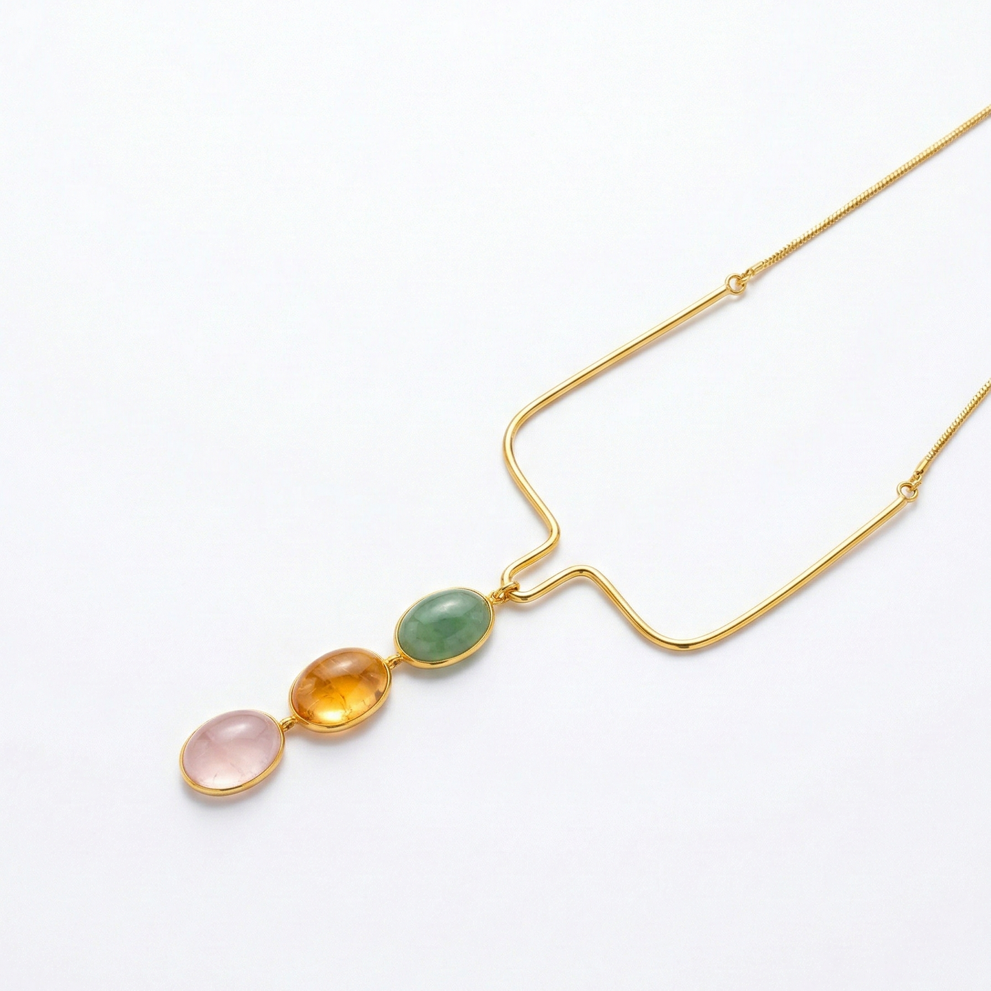 Gold necklace with three colored stones on a white background