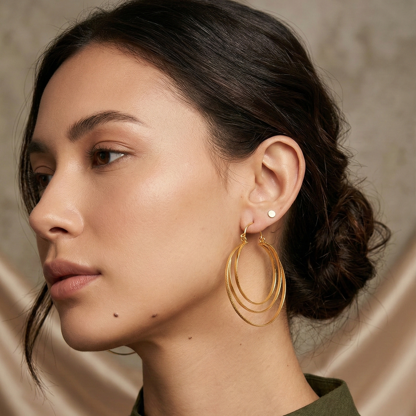 Woman wearing gold hoop earrings with a neutral background