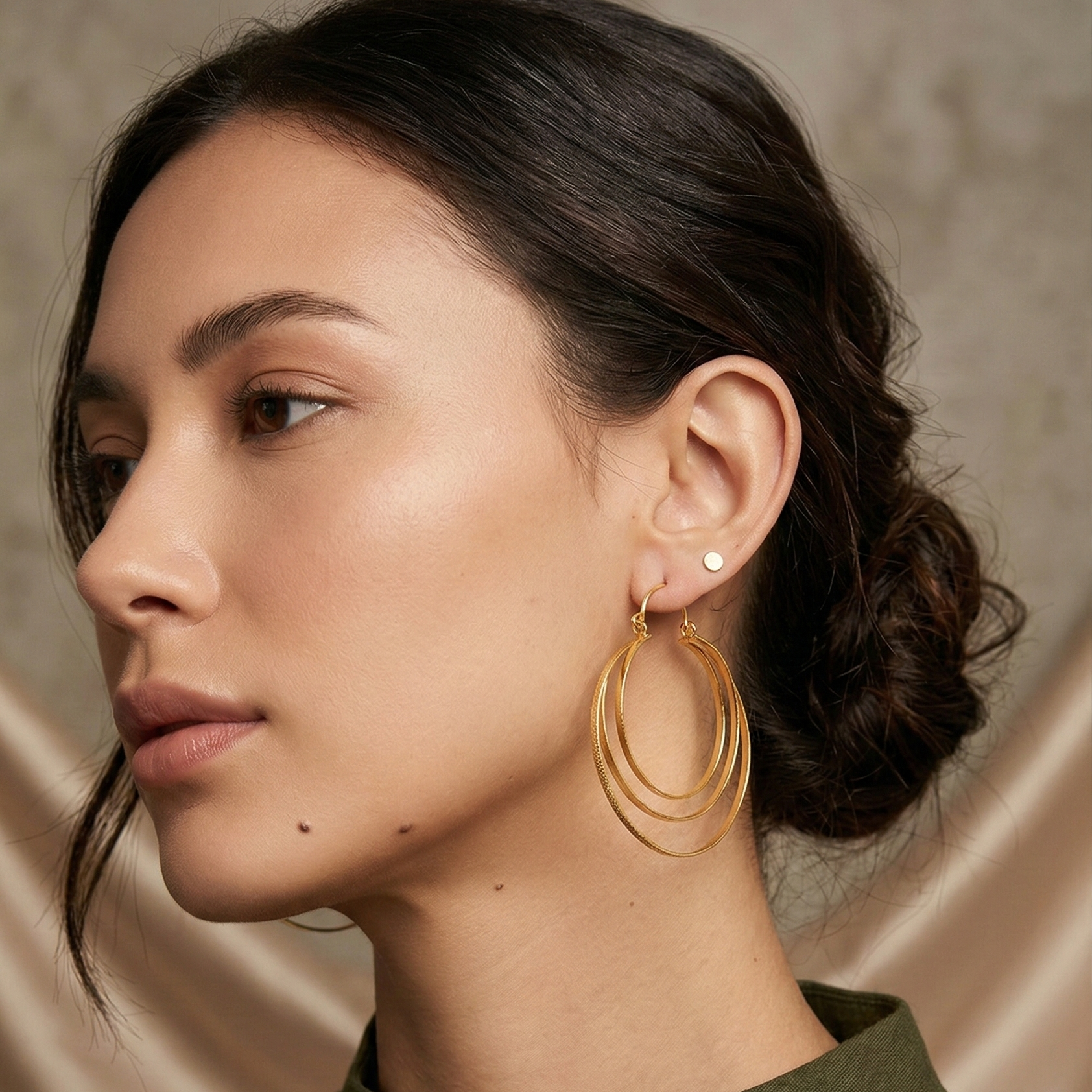 Woman wearing gold hoop earrings with a neutral background