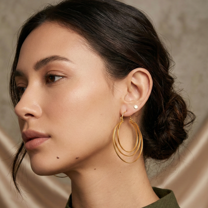 Woman wearing gold hoop earrings with a neutral background
