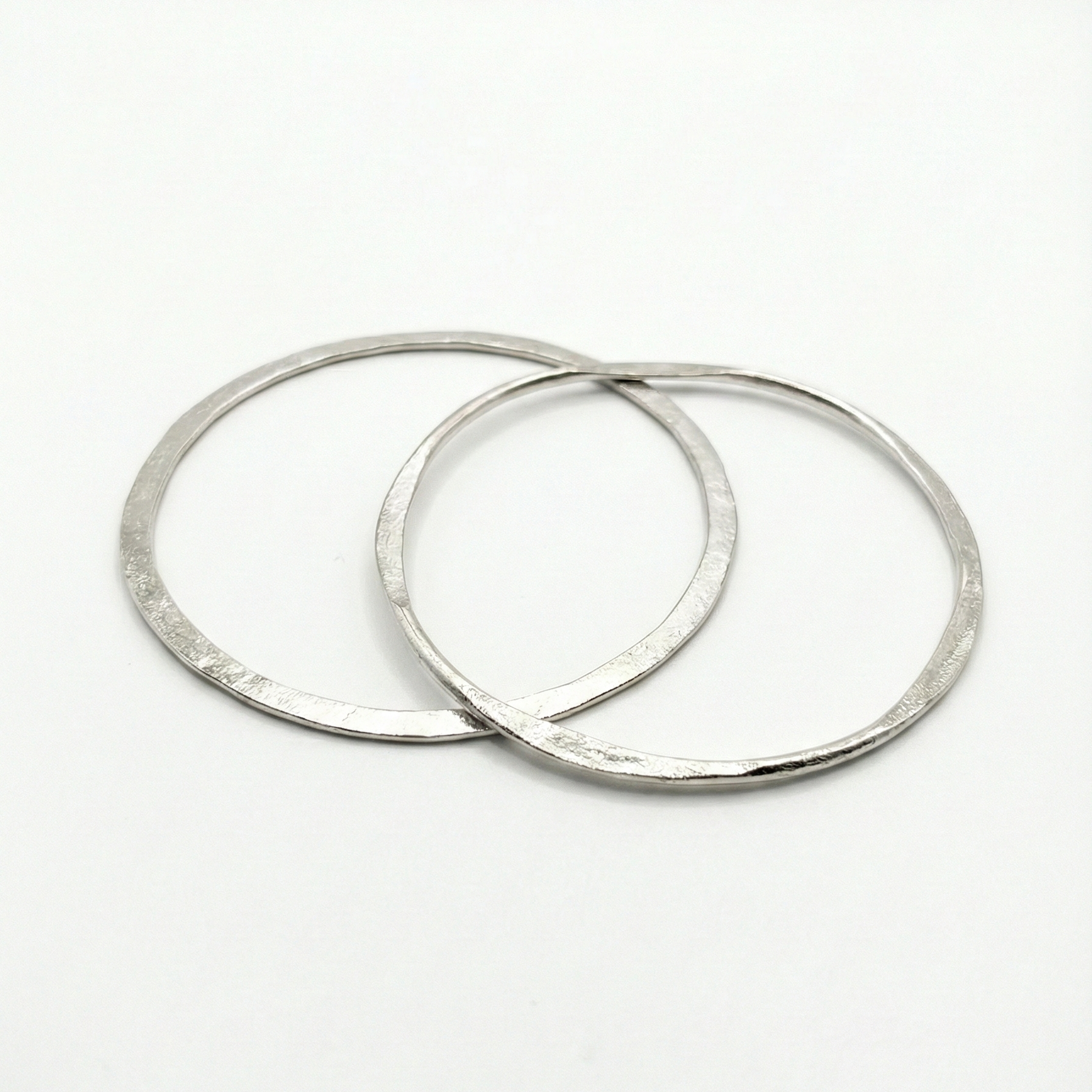 Two silver hammered texture bangles on a white background