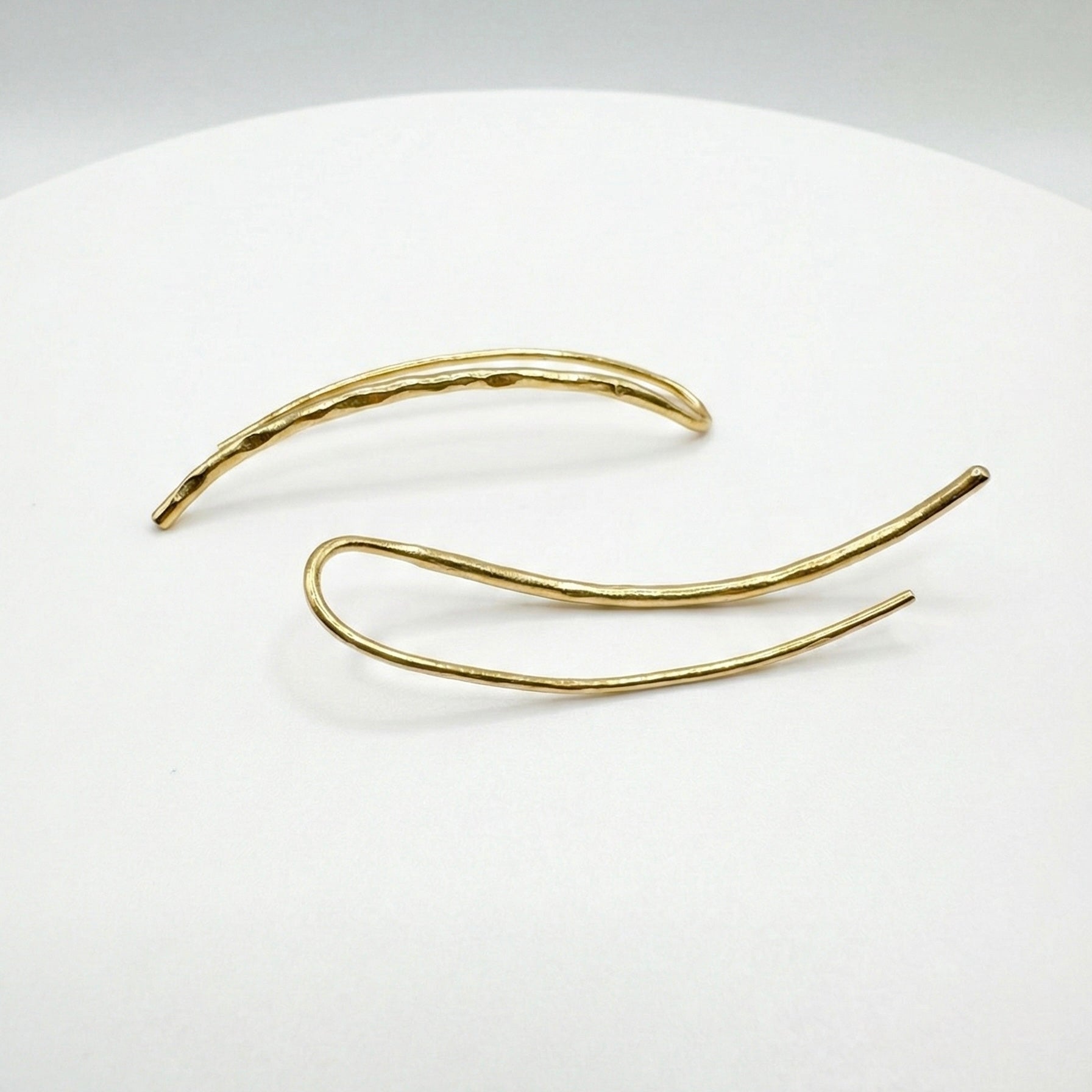 Gold ear climbers on a white plate