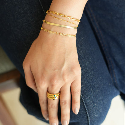 A person's wrist wearing a stack of gold-plated bracelets with a simple, elegant design.