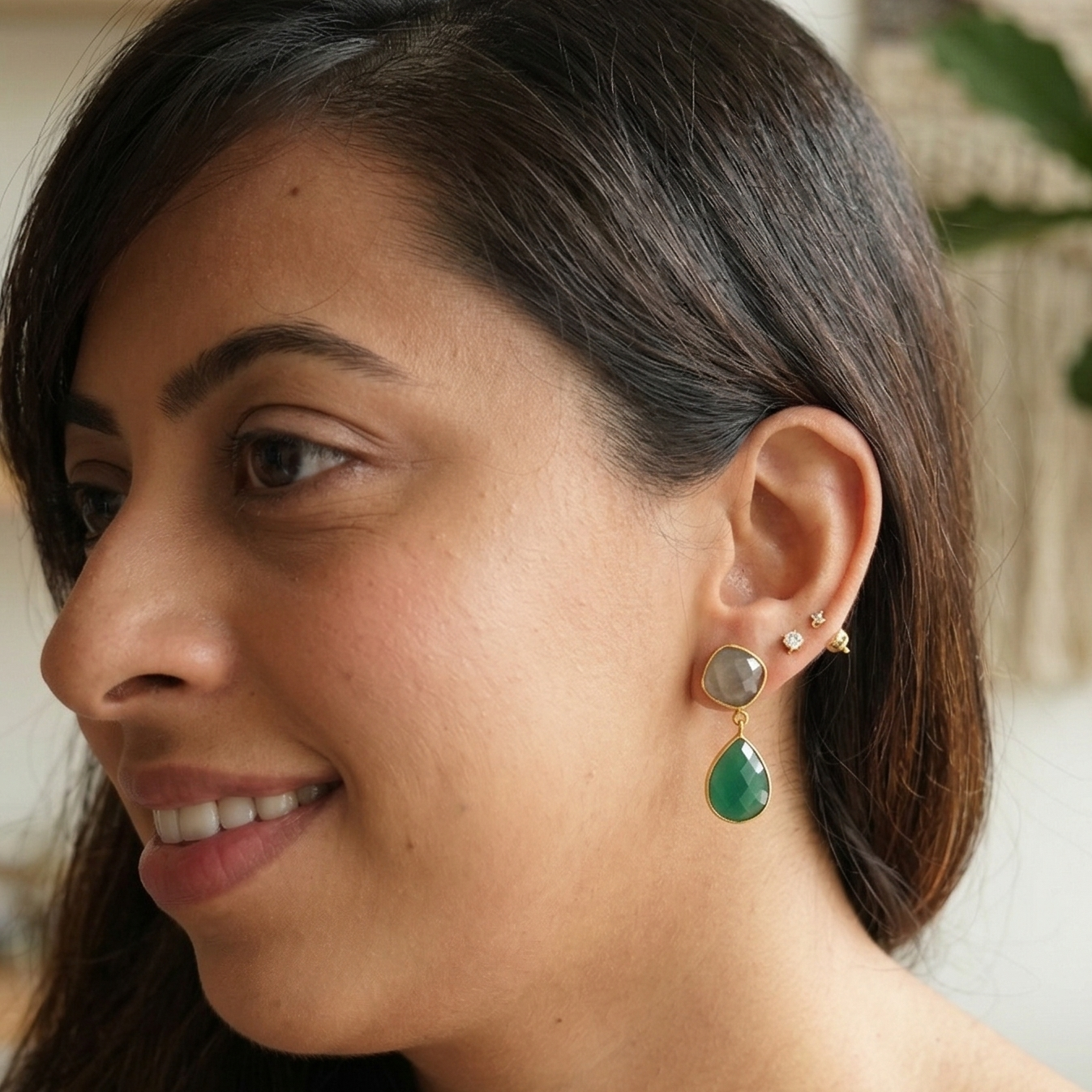 Woman wearing green earrings in a casual indoor setting