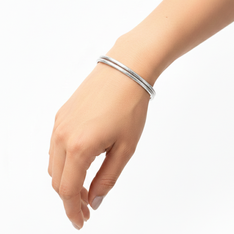Silver bangles on a wrist against a white background