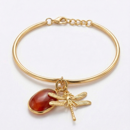 Gold bracelet with a carnelian stone and dragonfly charm on a white background