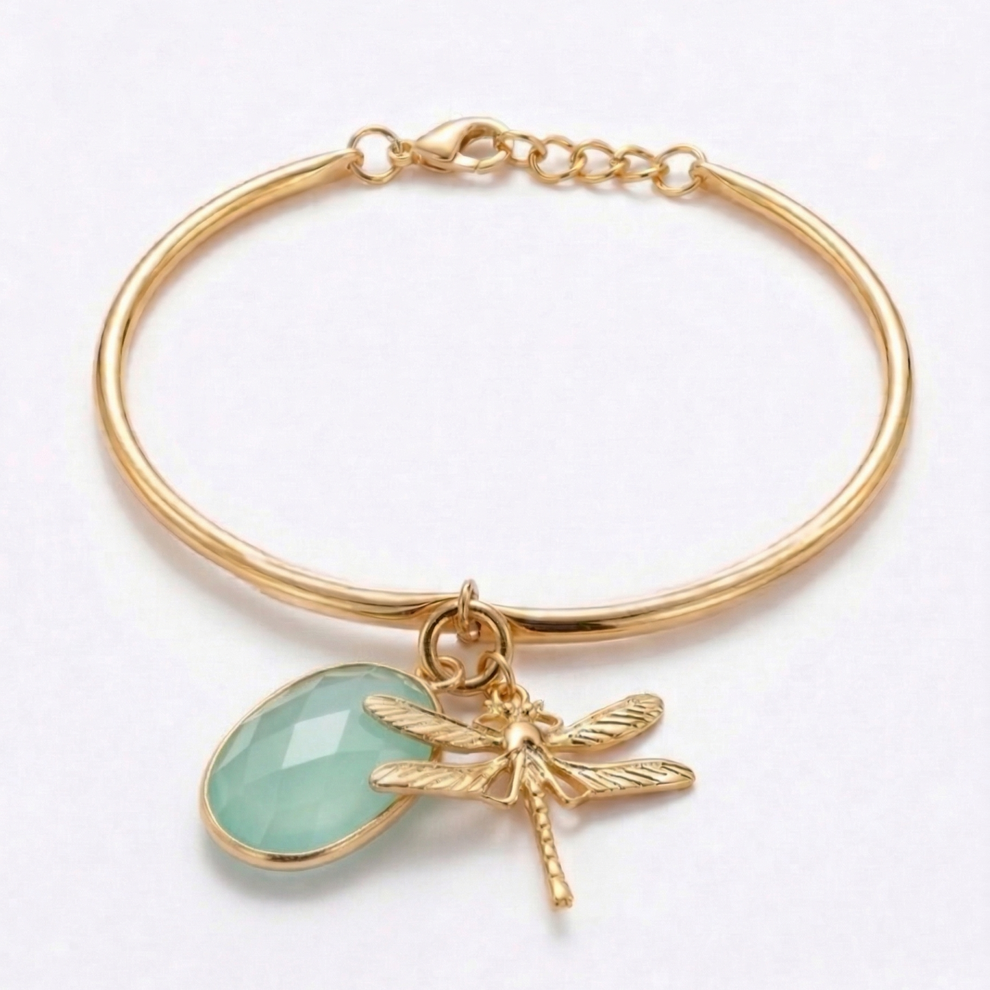 Gold bracelet with a greenstone charm and dragonfly detail on a white background