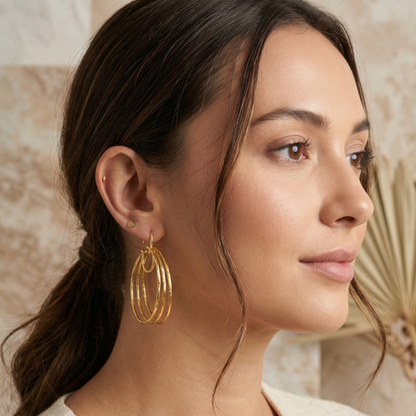Woman wearing gold hoop earrings with a neutral background