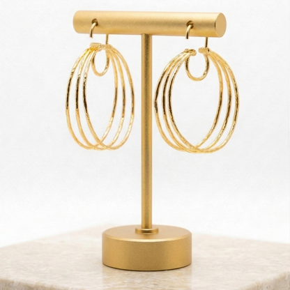 Gold hoop earrings on a matching gold stand with a white background
