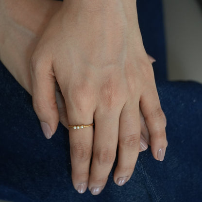 Close-up of a hand with a gold ring on a dark fabric background