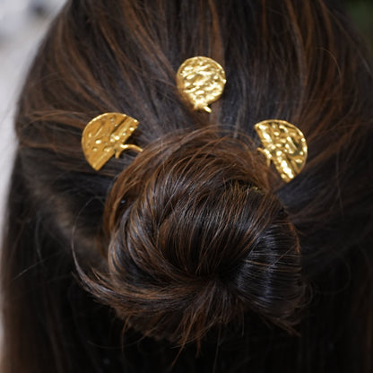 Close-up of a bun with gold hair accessories in dark hair.