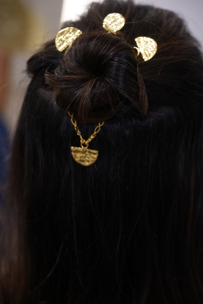 Close-up of a hair bun with gold hair ties on dark hair.