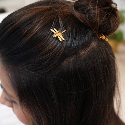 Close-up of a person's hair with a gold hair clip featuring a dragonfly design.