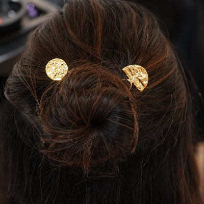 Close-up of a hair bun with gold hair ties against a blurred background