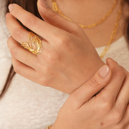 Close-up of a person wearing gold jewelry including a ring and bracelet.