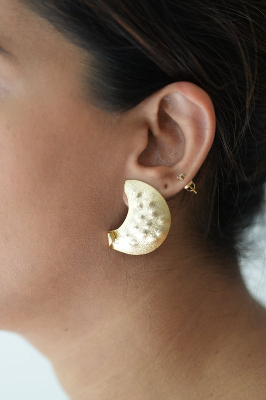 Close-up of a woman wearing gold earrings with a blurred background